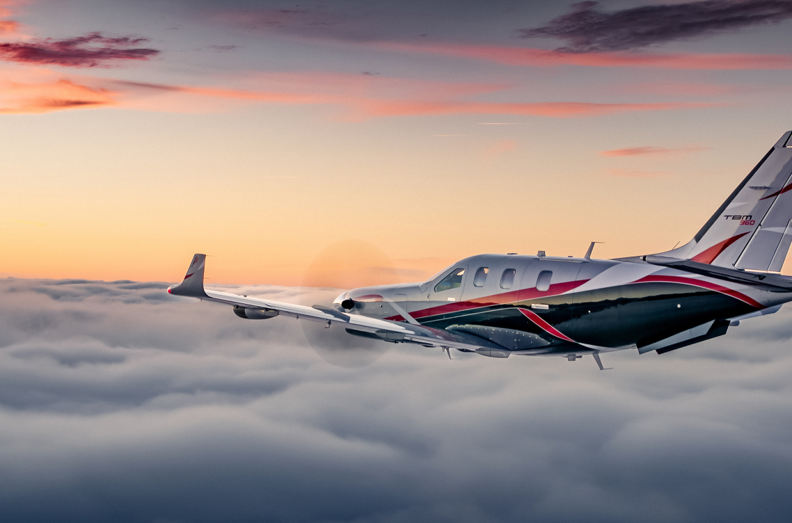 plane flying over clouds with the sun setting